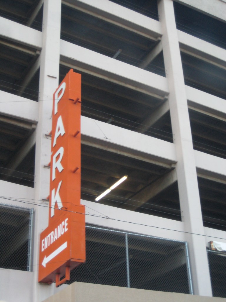 Orange park sign affixed to the side of a parking garage
