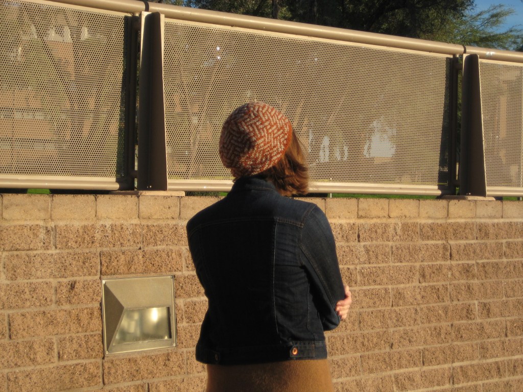 Vega Beret Young woman standing beside a wall while wearing an orange-and-gray tam