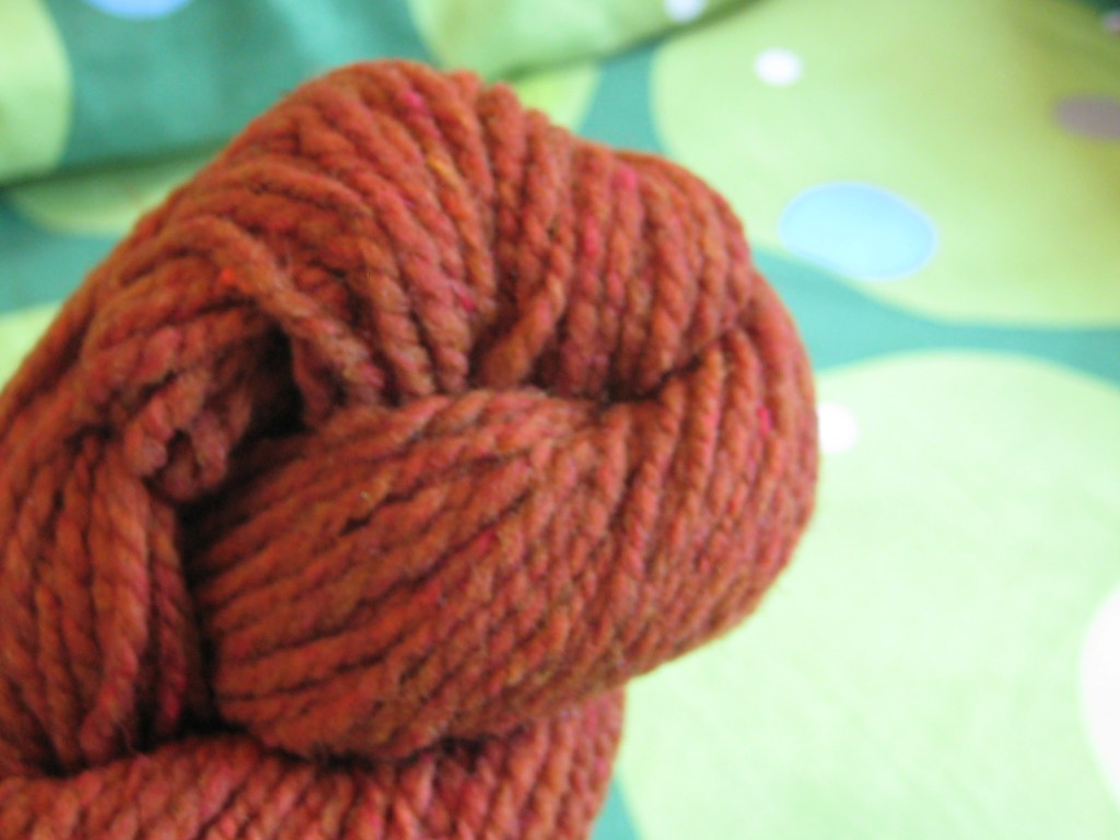 Skein of orange yarn against a green background