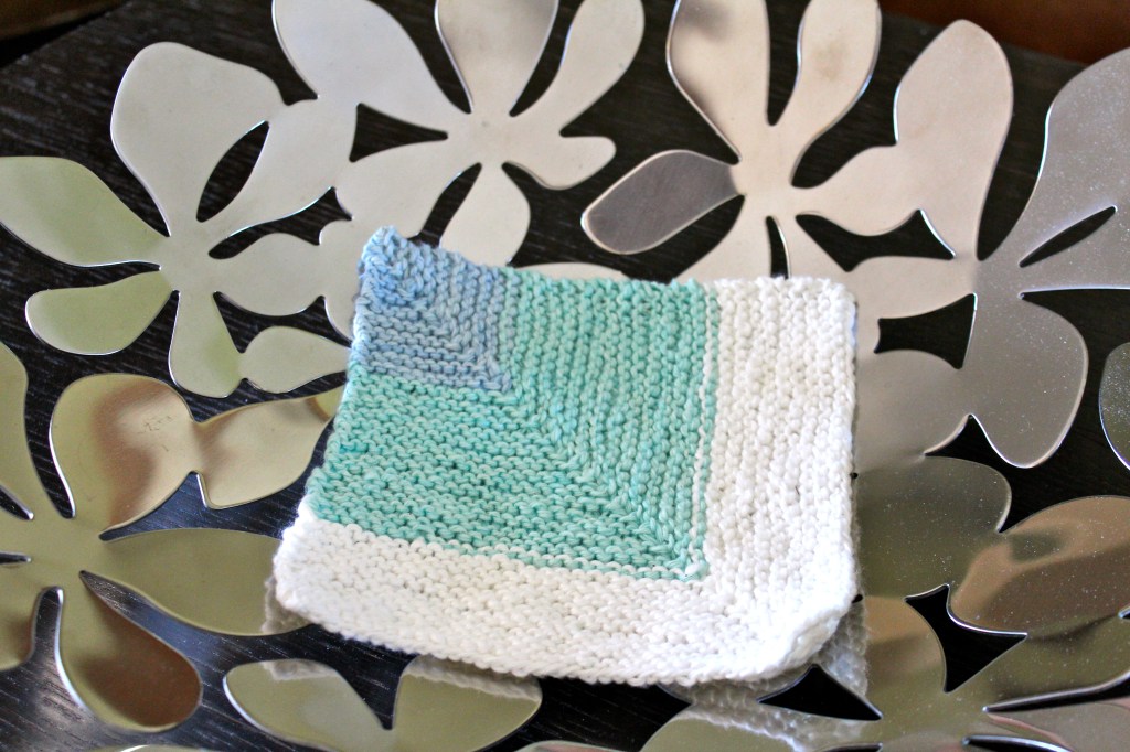 Blue, turquoise, and white washcloth in a silver bowl.