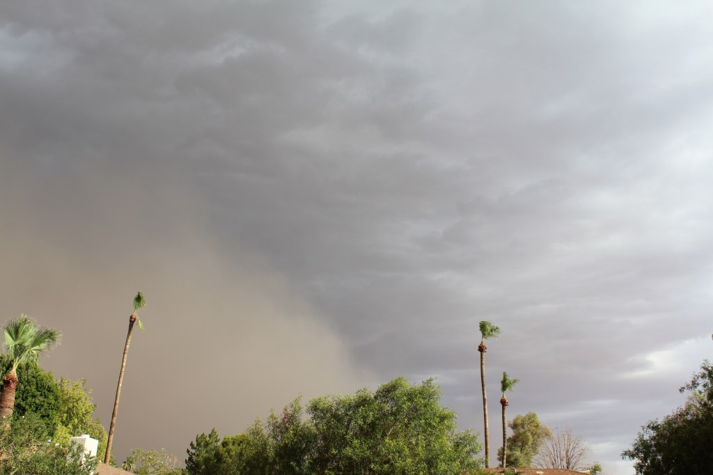 Brown dust storm blowing across cloudy sky