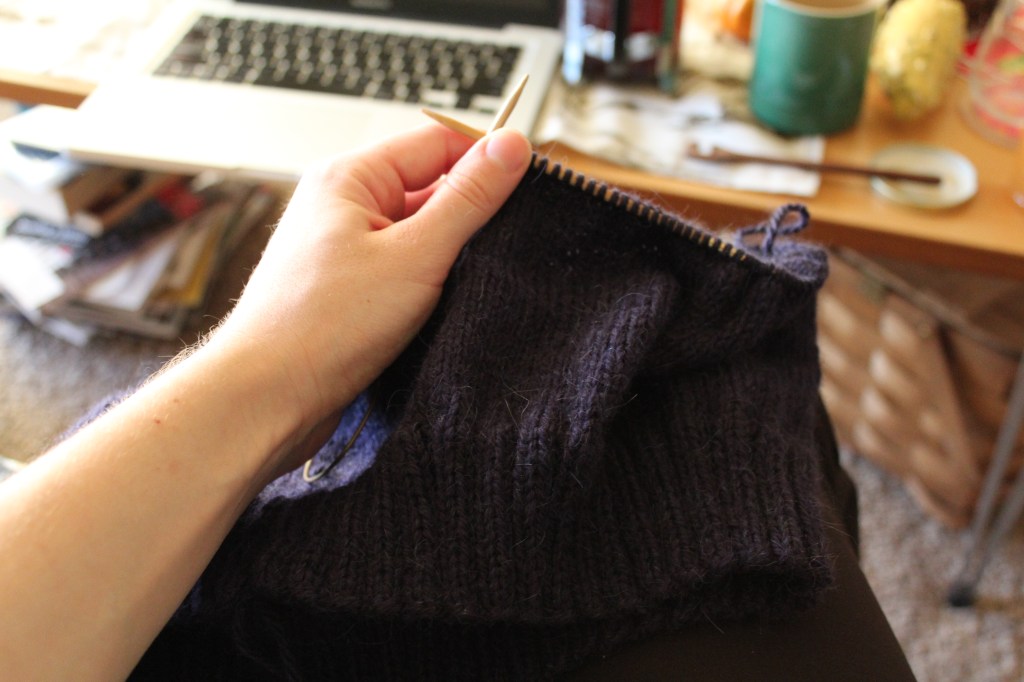 Hand holding purple knitting