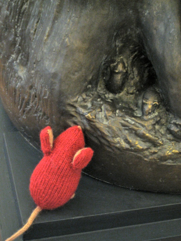 Red knitted mouse next to mice on bronze statue