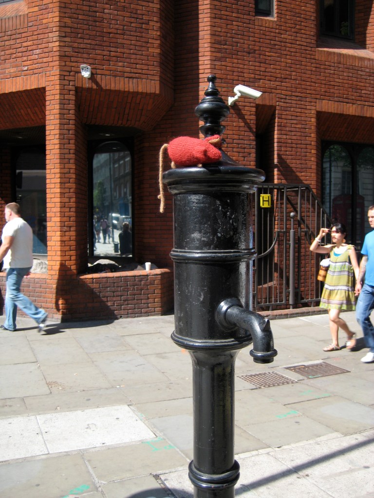 Red knitted mouse sitting on the Broad Street Pump