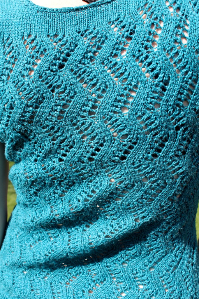 Detail of lace knitting on a teal tank top