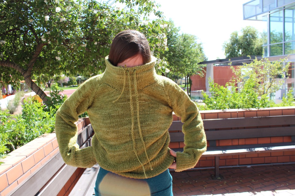 Girl putting on a green knitted sweater
