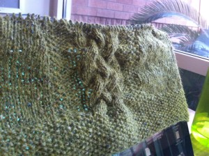 Green cabled knitting atop a laptop