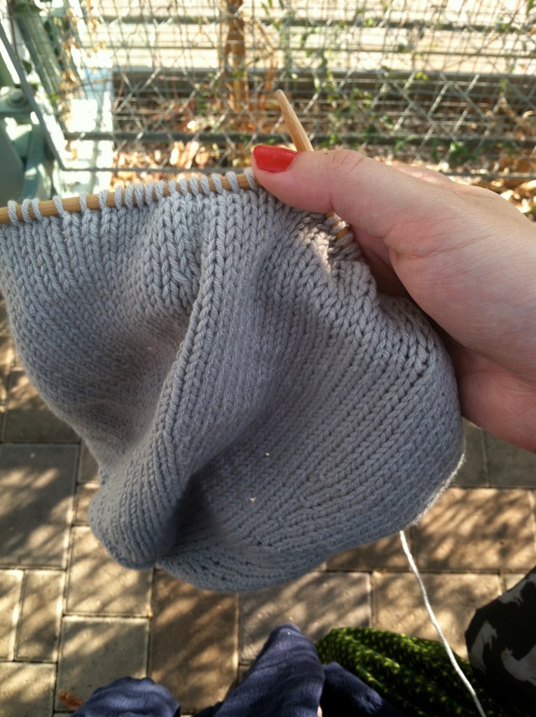 Woman with red nail polish holding gray knitting