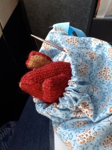 Red knitted mouse peeking its head out of a knitting bag