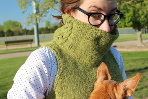 Woman holding a small dog and wearing a cowl neck vest