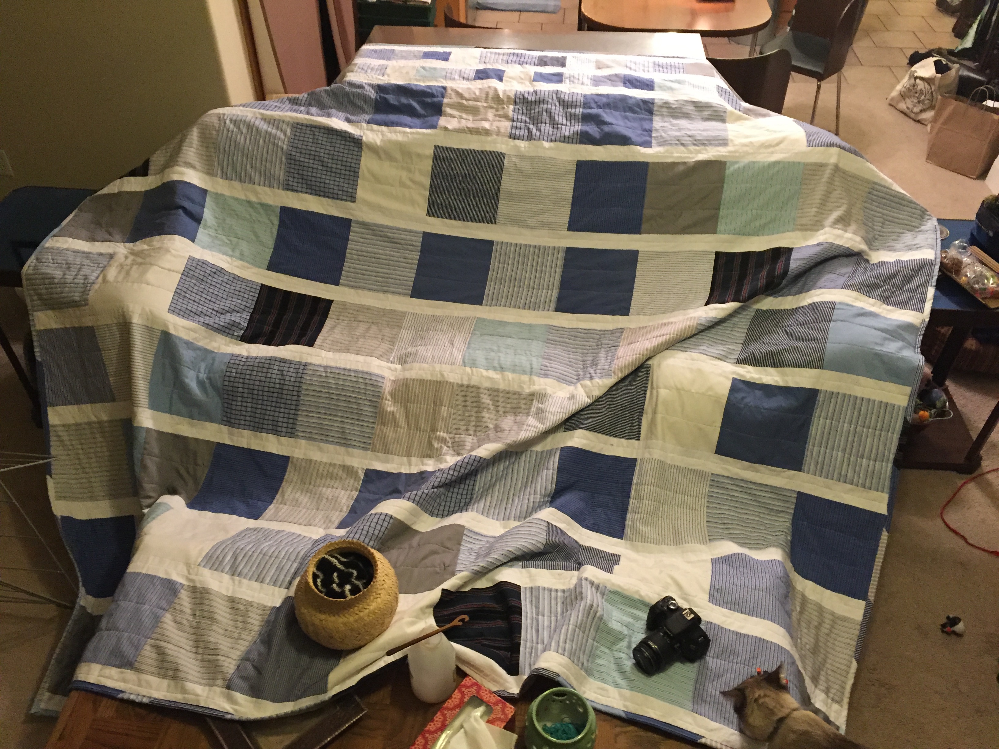 Large blue and white quilt spread out across a couch and two tables