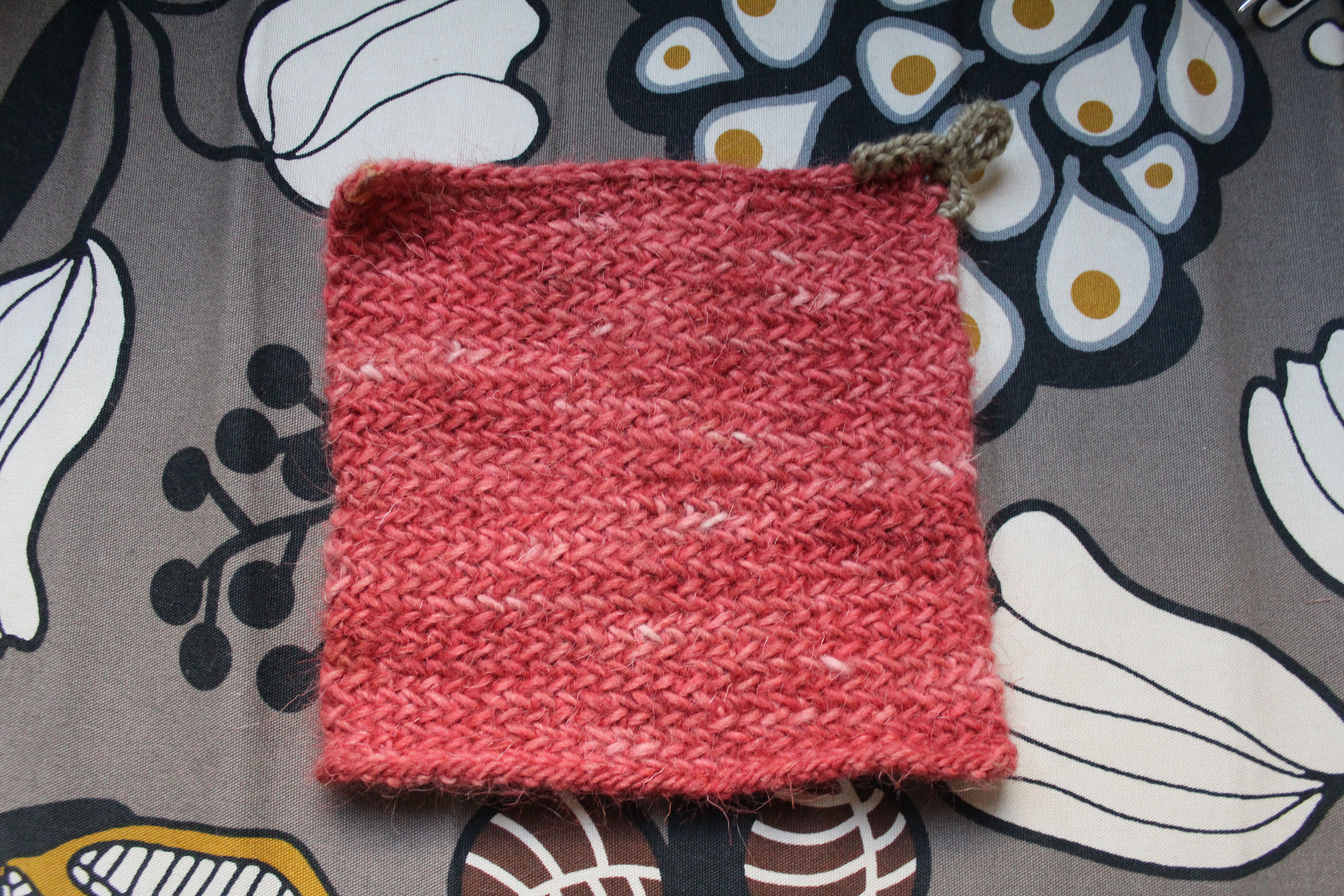 Pink knitted potholder with crocheted hook loop