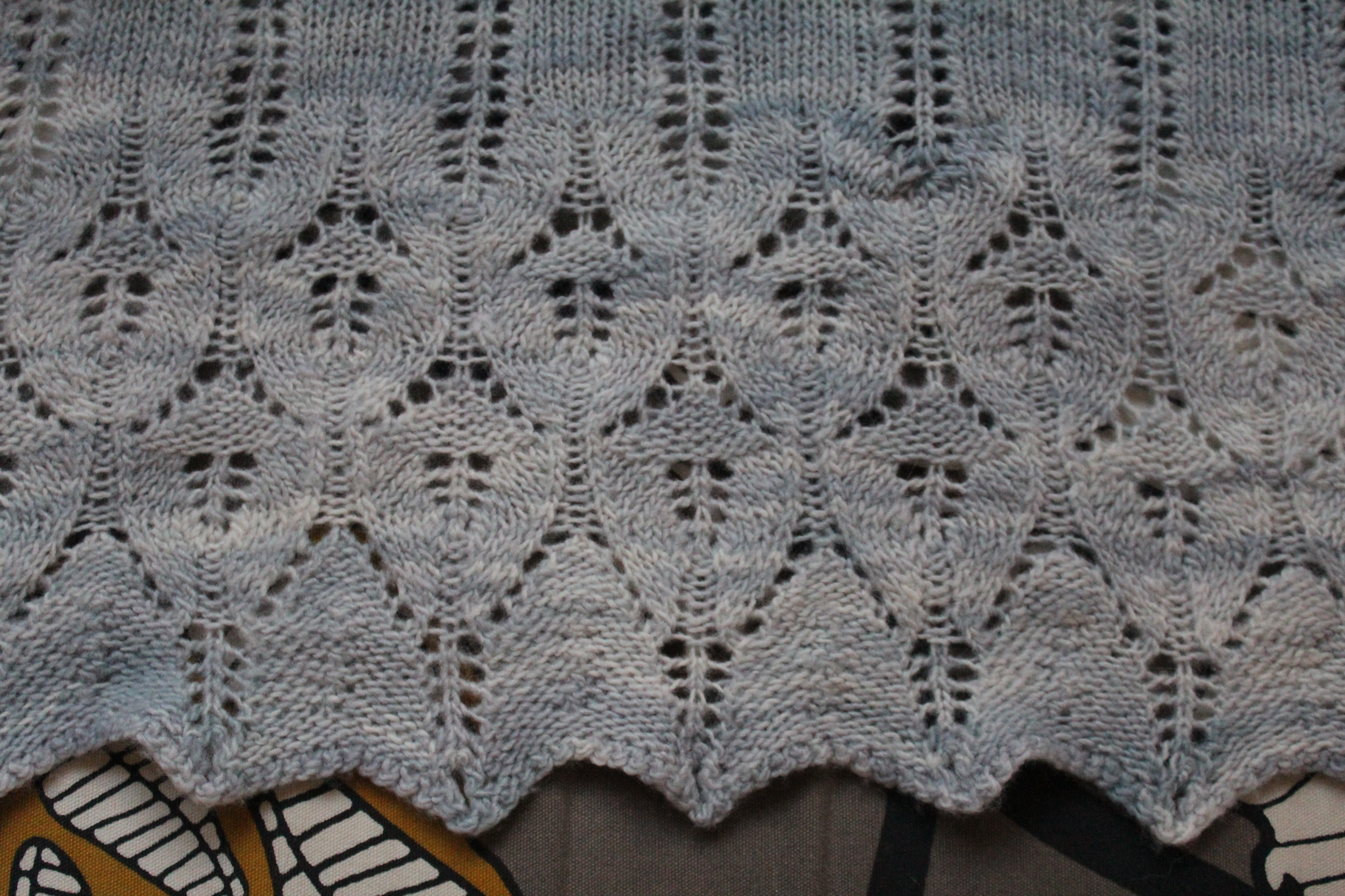 Pale blue knitted Icarus shawl with mended moth hole