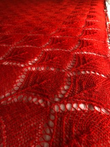 Flower basket motif in orange-red laceweight blocked against a white sheet