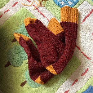 Maroon and gold Classic Socks folded up against a child's play rug