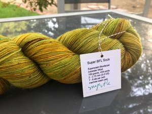 Hello Yarn Super BFL Sock in Myrtle, a yellowy green, on a glass table