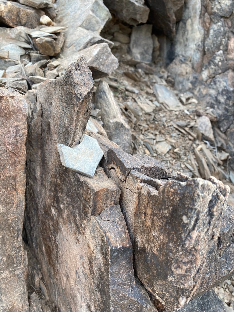 Heart shaped rock balanced on an outcropping of gray rocks 